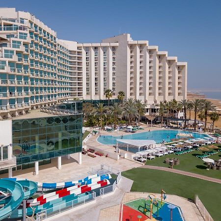 Leonardo Club Hotel Dead Sea Неве-Зогар Екстер'єр фото The image shows a large hotel complex alongside a pool area. The hotel features modern architecture with multiple levels and numerous balconies. In front of the hotel, there is a recreational area with a swimming pool, water slides, and lounging chai